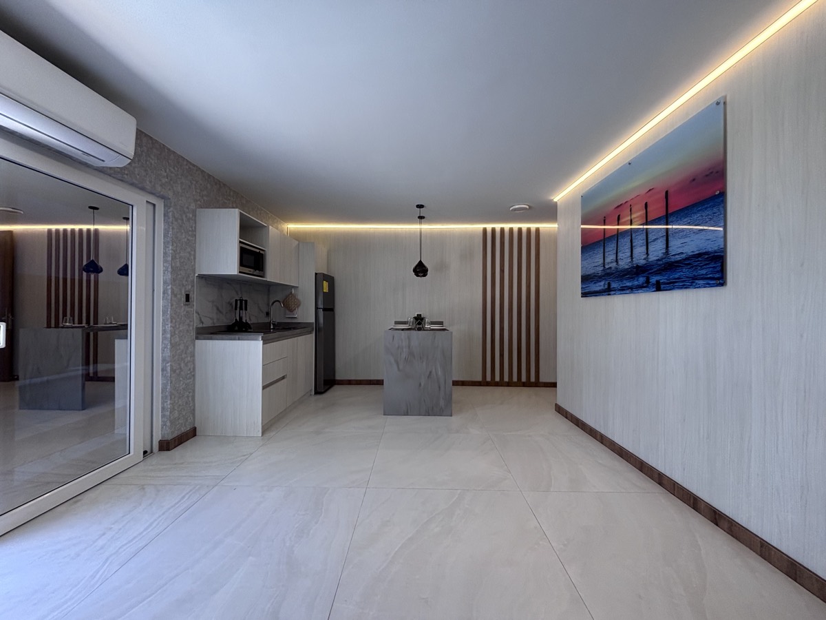 The open living and kitchen space inside a Casabella suite, with recessed lighting and a sliding door to the backyard.